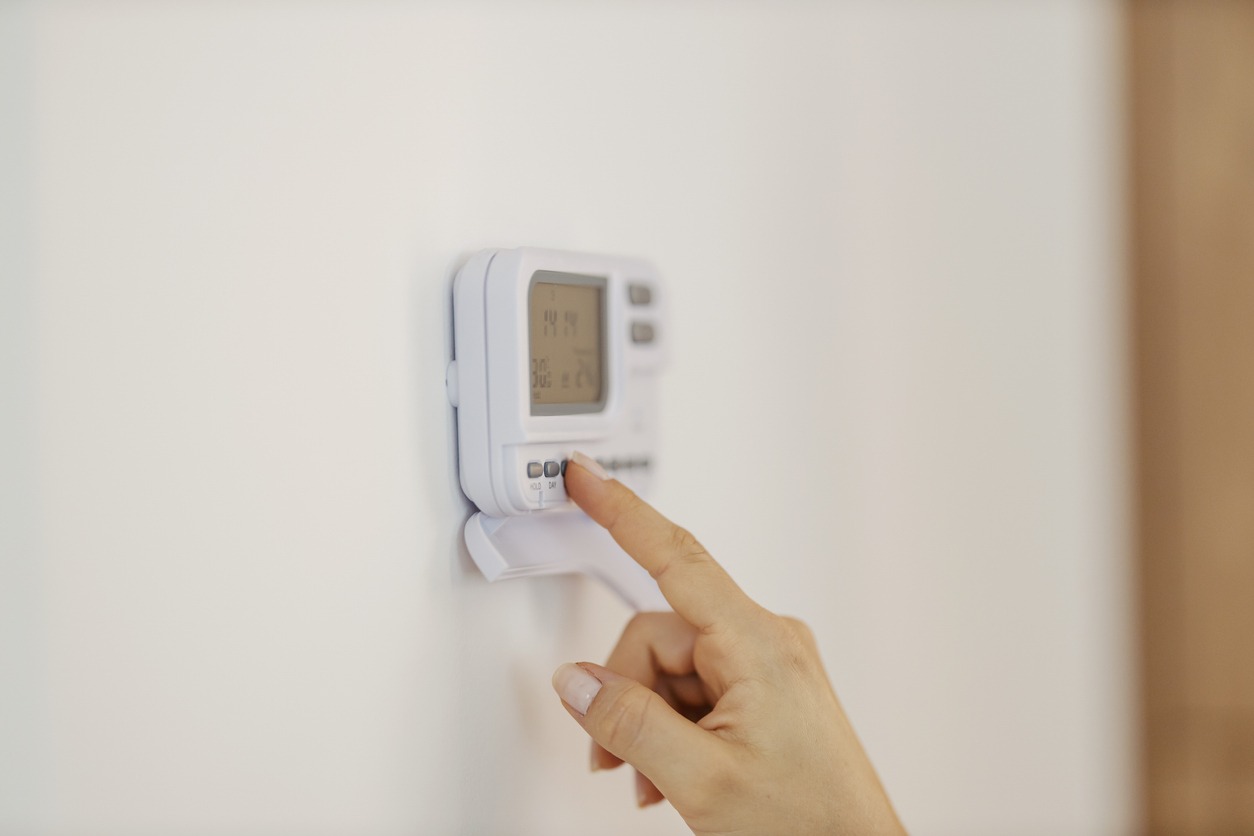 Hand adjusting the temperature in a home on a thermostat