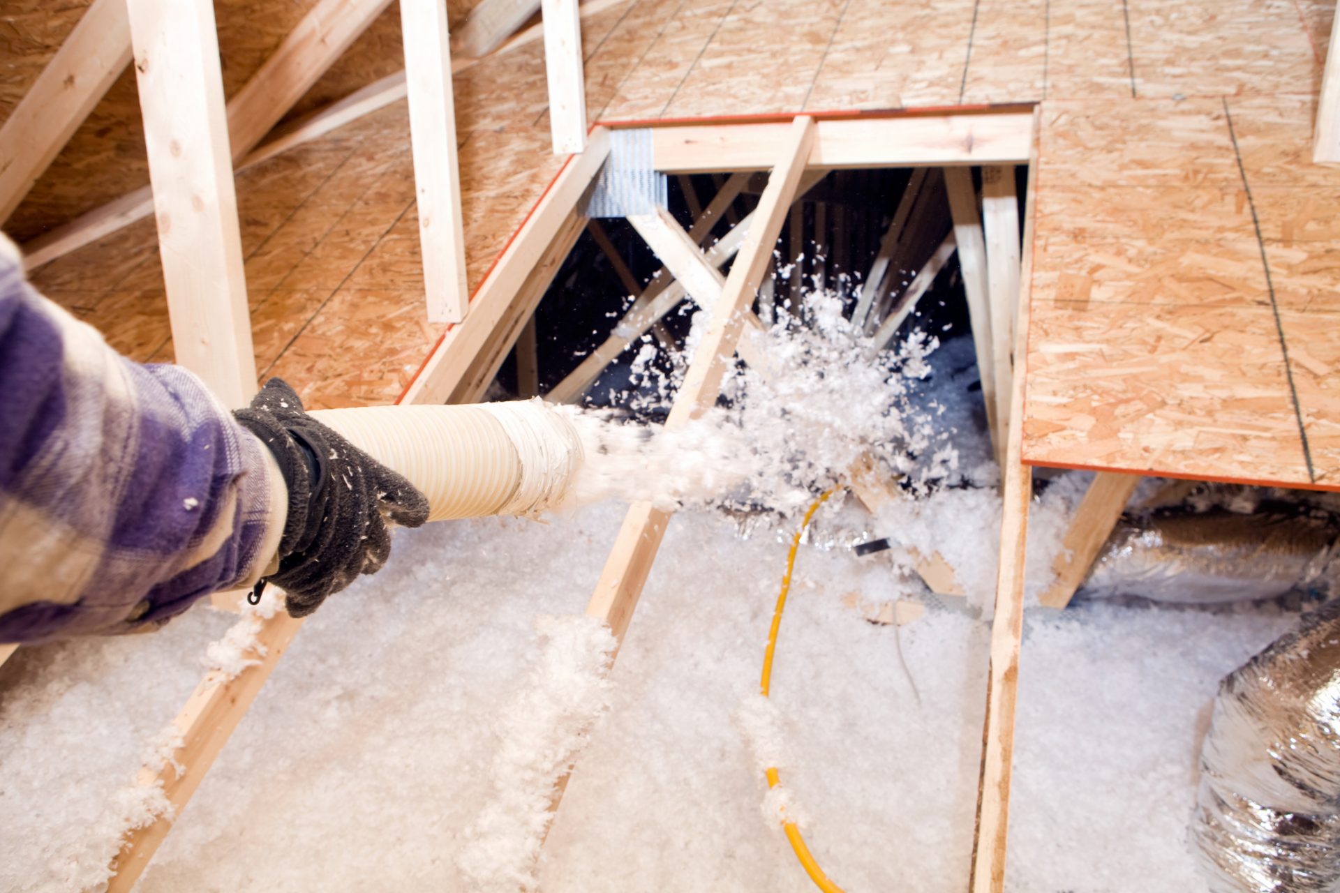 Worker spraying fibreglass foam into a loft.