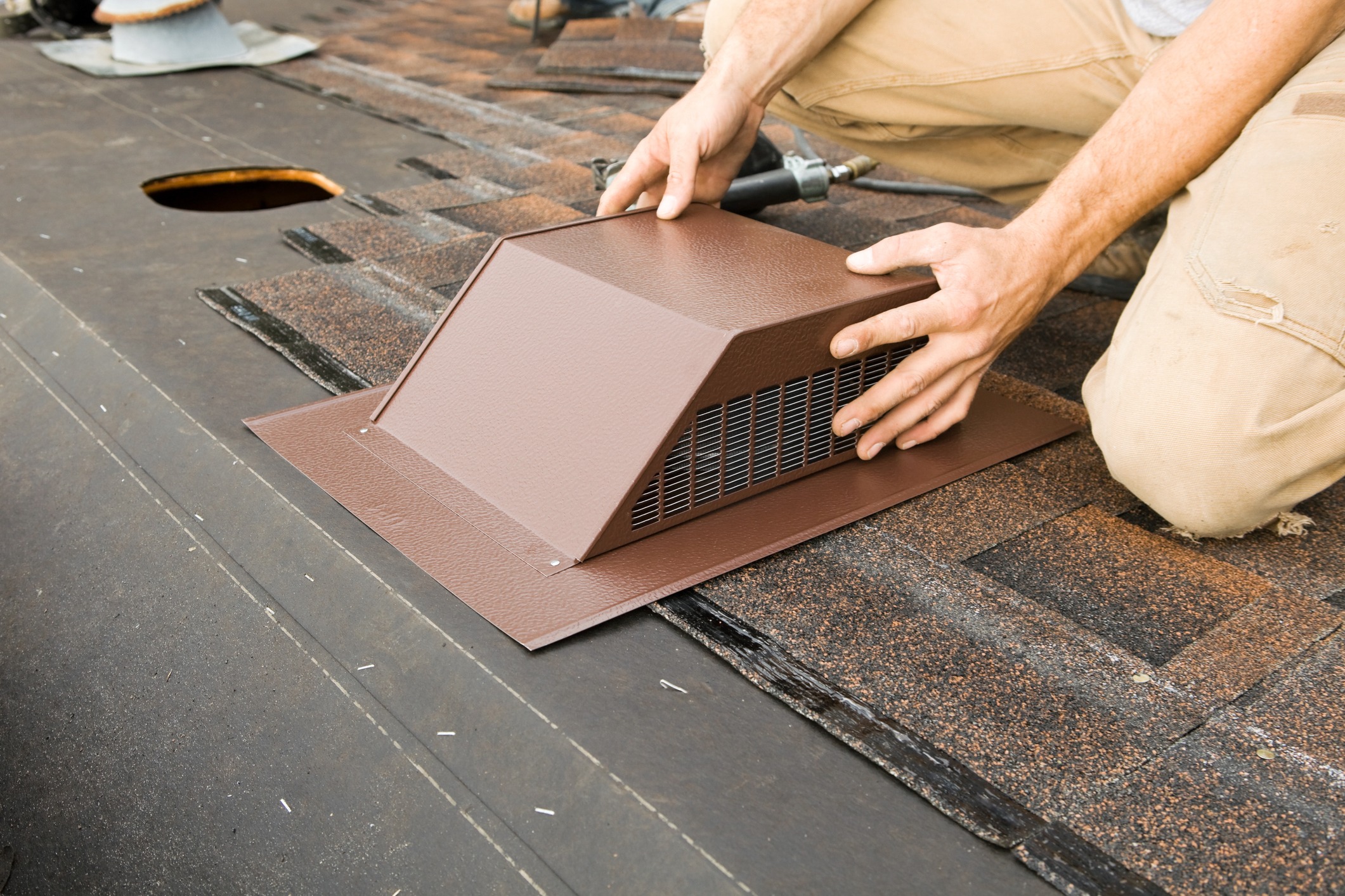 A worker installing a vent on a roof.